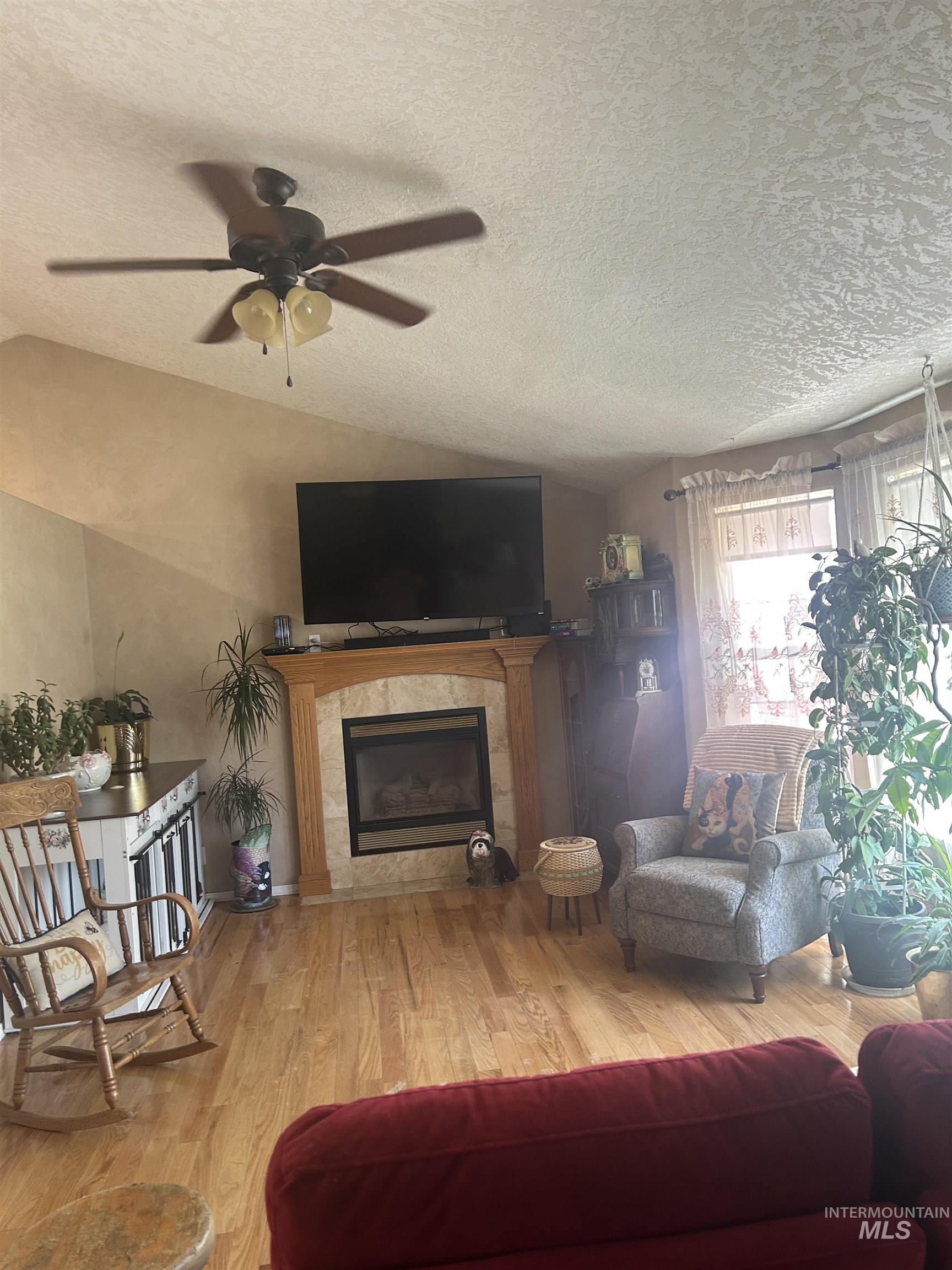 1444 East Doberman Street Meridian, ID 83642 - Photo 30 of 31 Living area featuring wood-finish flooring, a vaulted ceiling, and a fireplace with a tile surround and wood mantel