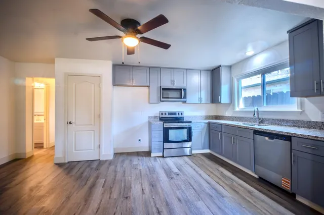 a kitchen with granite countertop a stove a sink dishwasher and a refrigerator with wooden floor