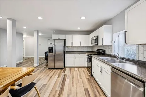 a large kitchen with stainless steel appliances kitchen island granite countertop a sink and cabinets