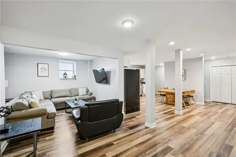 a living room with furniture a refrigerator and a flat screen tv