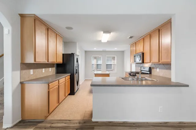 a large kitchen with granite countertop a large window and stainless steel appliances