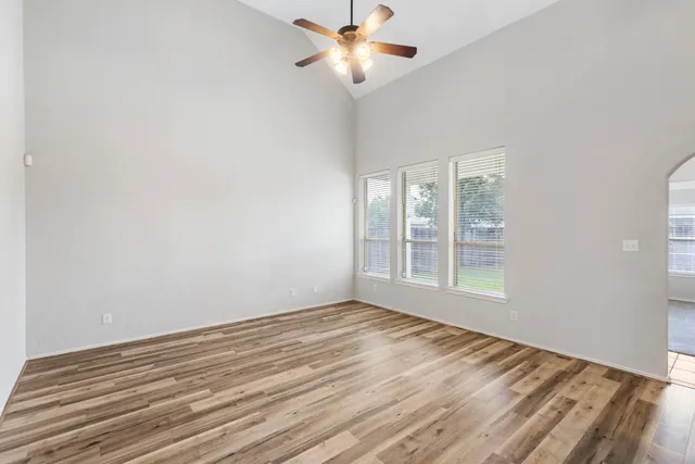 a view of an empty room with window and a kitchen