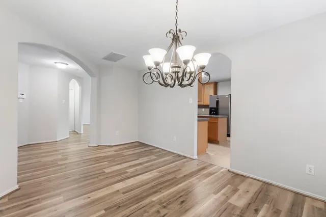 a view of a chandelier in big room with wooden floor