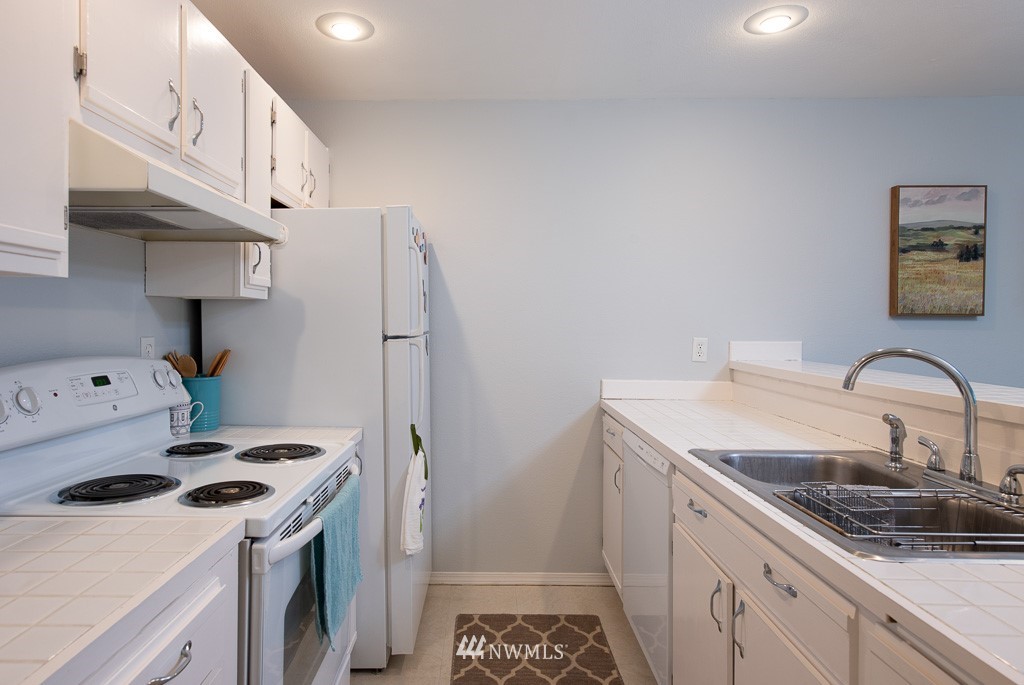 2152 North 112th Street, Unit 303 Seattle, WA 98133 - Photo 9 of 19 a kitchen with stainless steel appliances a sink a stove and a refrigerator