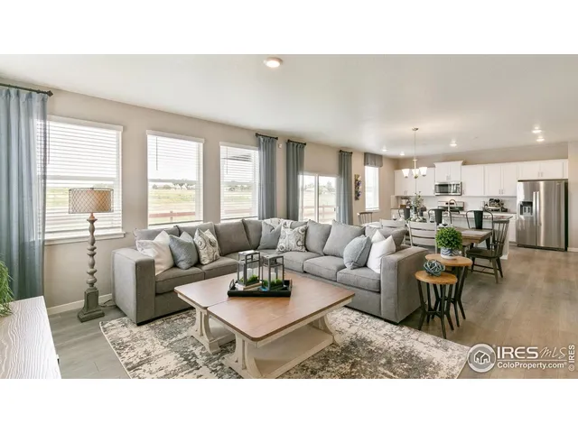 a living room with furniture a large window and wooden floor