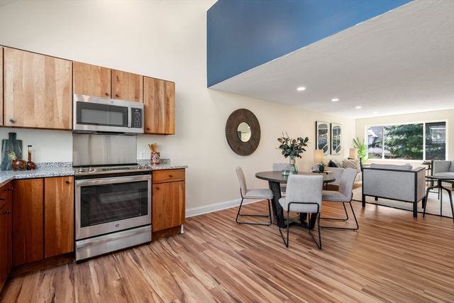 a kitchen with stainless steel appliances a stove a microwave a sink a dining table and chairs