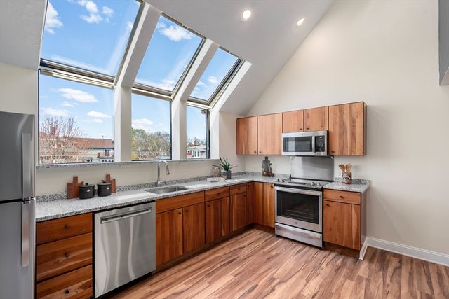 a kitchen with stainless steel appliances granite countertop wooden cabinets a sink and a large window