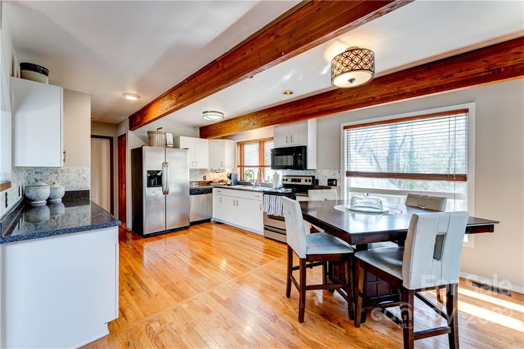 25030 Riley Lane Tega Cay, SC 29708 - Photo 8 of 48 a kitchen with stainless steel appliances granite countertop a stove top oven a sink a dining table and chairs with wooden floor