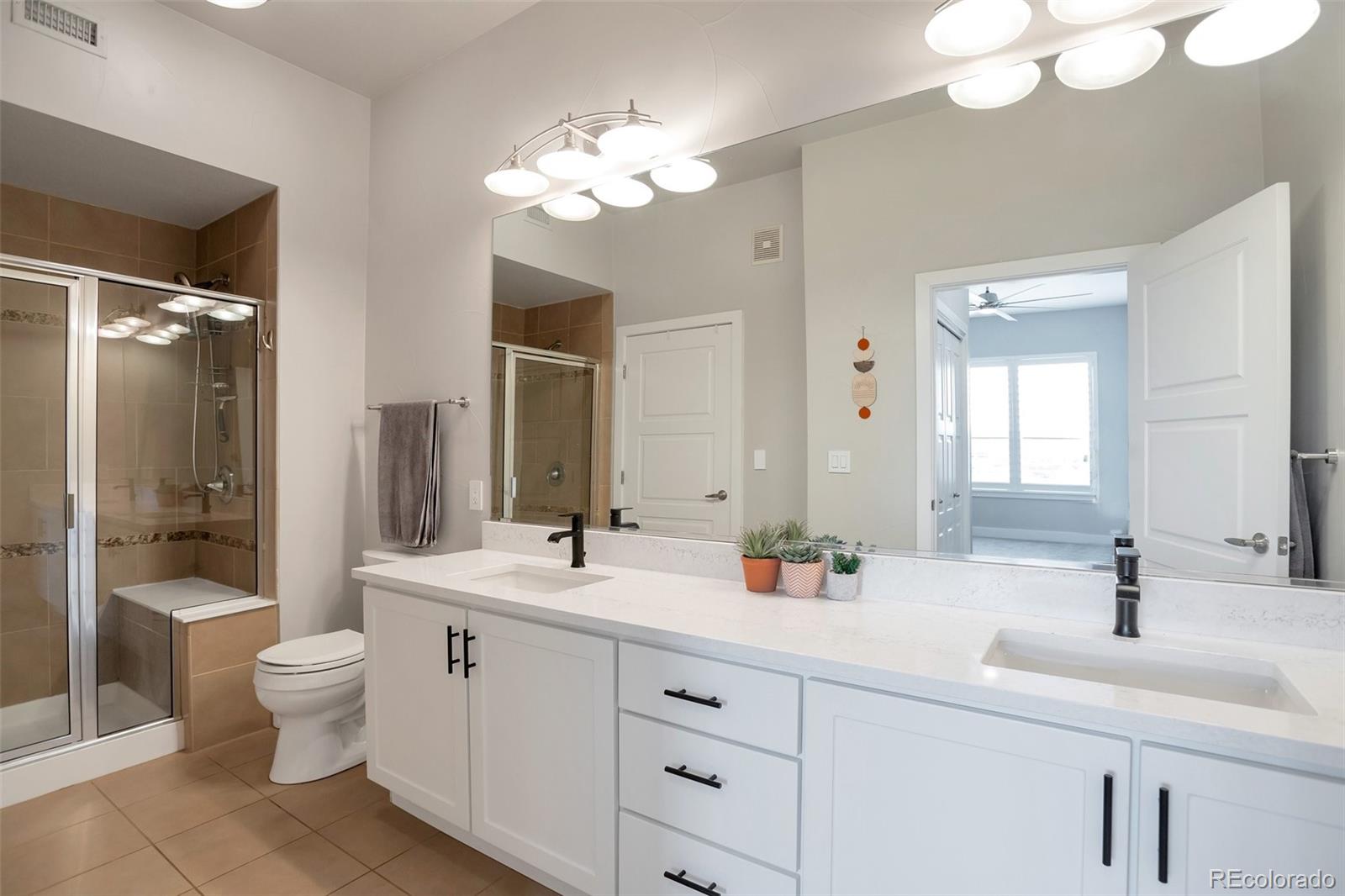 10111 Inverness Main Street, Unit 301 Englewood, CO 80112 - Photo 12 of 28 a bathroom with a double vanity sink mirror and toilet