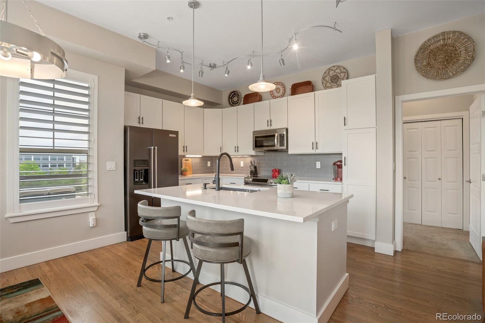 10111 Inverness Main Street, Unit 301 Englewood, CO 80112 - Photo 8 of 28 a kitchen with kitchen island appliances cabinets and wooden floor