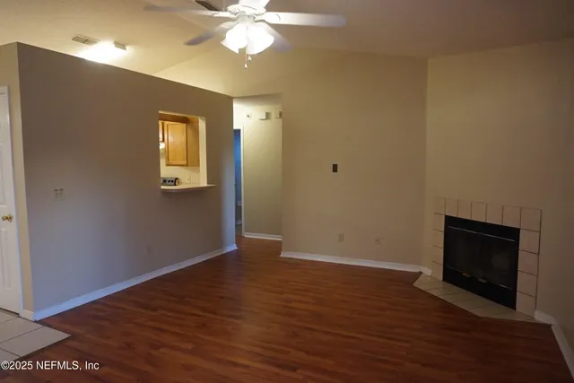 a view of an empty room with wooden floor and a fireplace