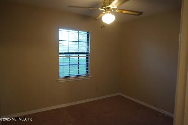 an empty room with windows and fan