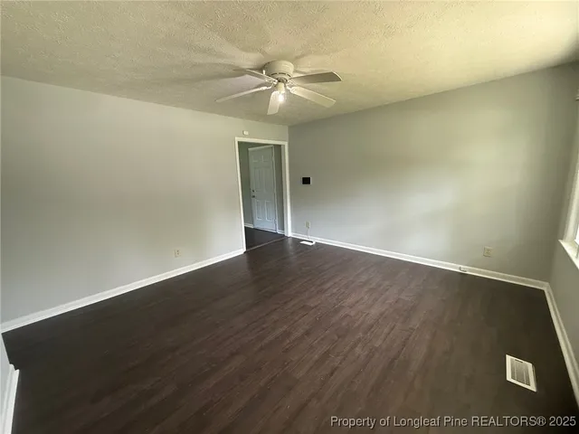 an empty room with wooden floor and fan