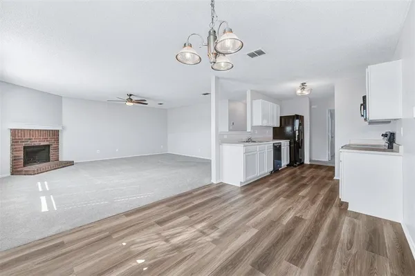 a view of kitchen and empty room with wooden floor