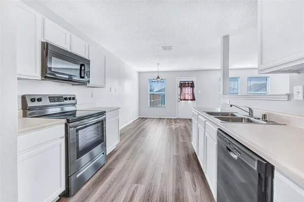 a kitchen with stainless steel appliances granite countertop a sink stove microwave and refrigerator