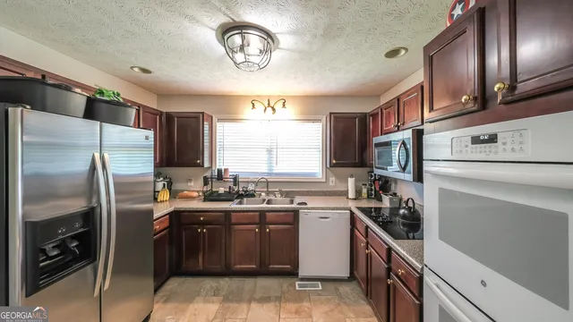 a kitchen with a sink stainless steel appliances cabinets and a window