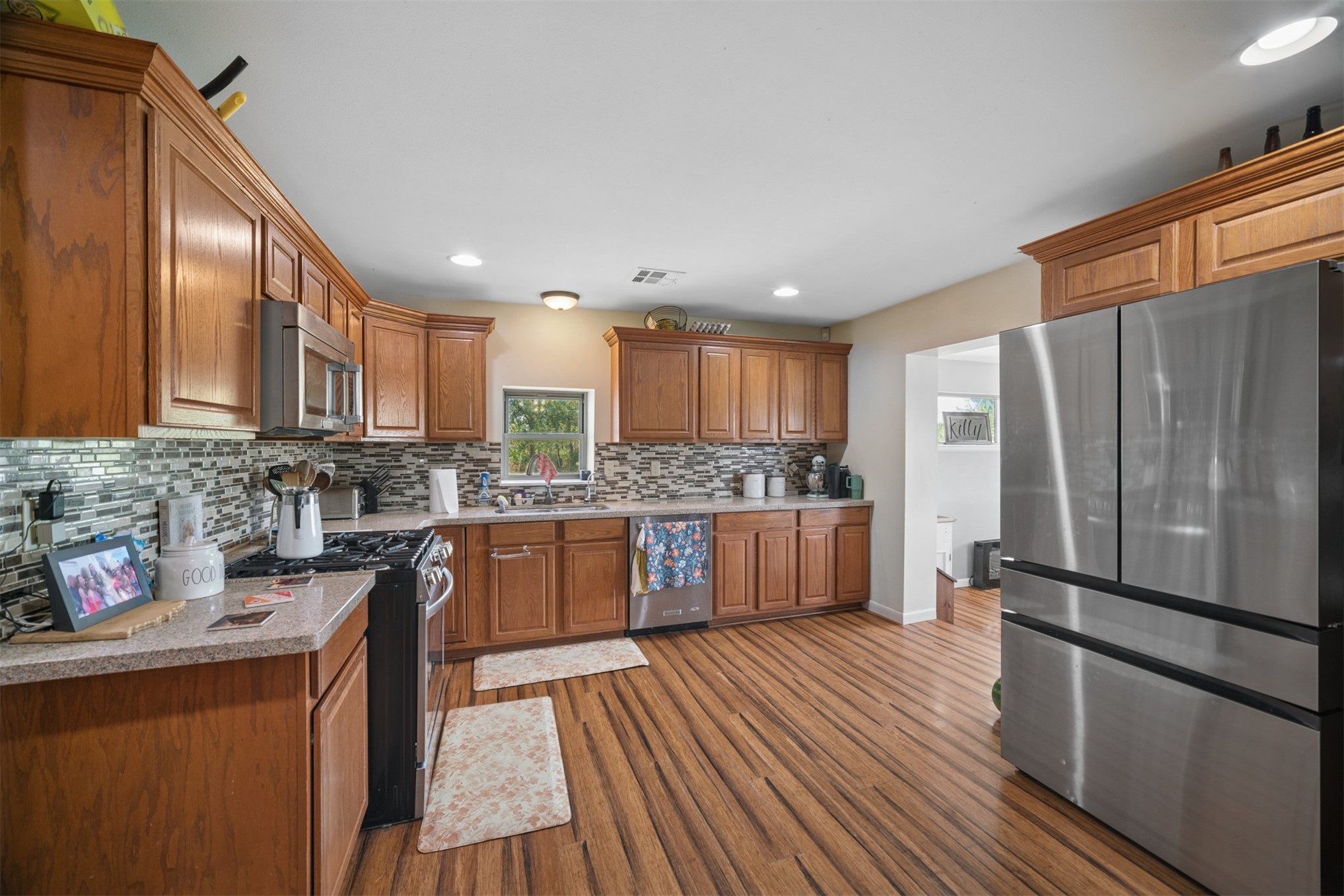 49301 South 360 Road Pawnee, OK 74058 - Photo 10 of 44 Kitchen featuring wood-finish flooring, wood cabinetry with crown molding, a tiled backsplash, and stainless steel appliances