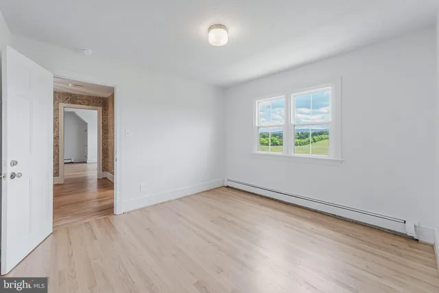 an empty room with wooden floor and ceiling fan