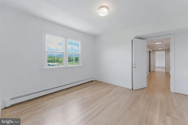 an empty room with wooden floor chandelier fan and windows