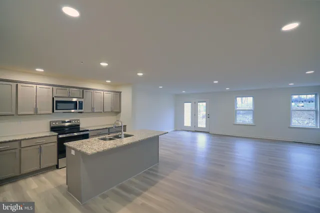 a kitchen with stainless steel appliances granite countertop a sink a stove top oven a counter space and cabinets