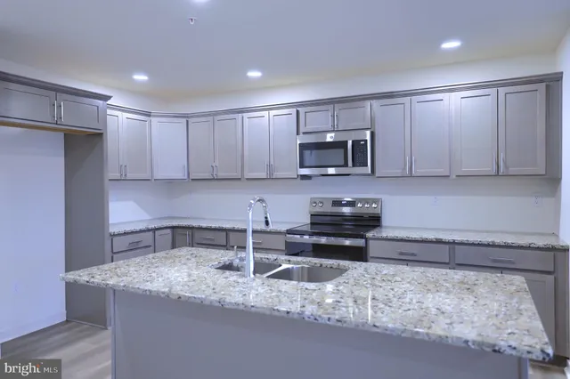 a kitchen with stainless steel appliances granite countertop a sink stove and microwave