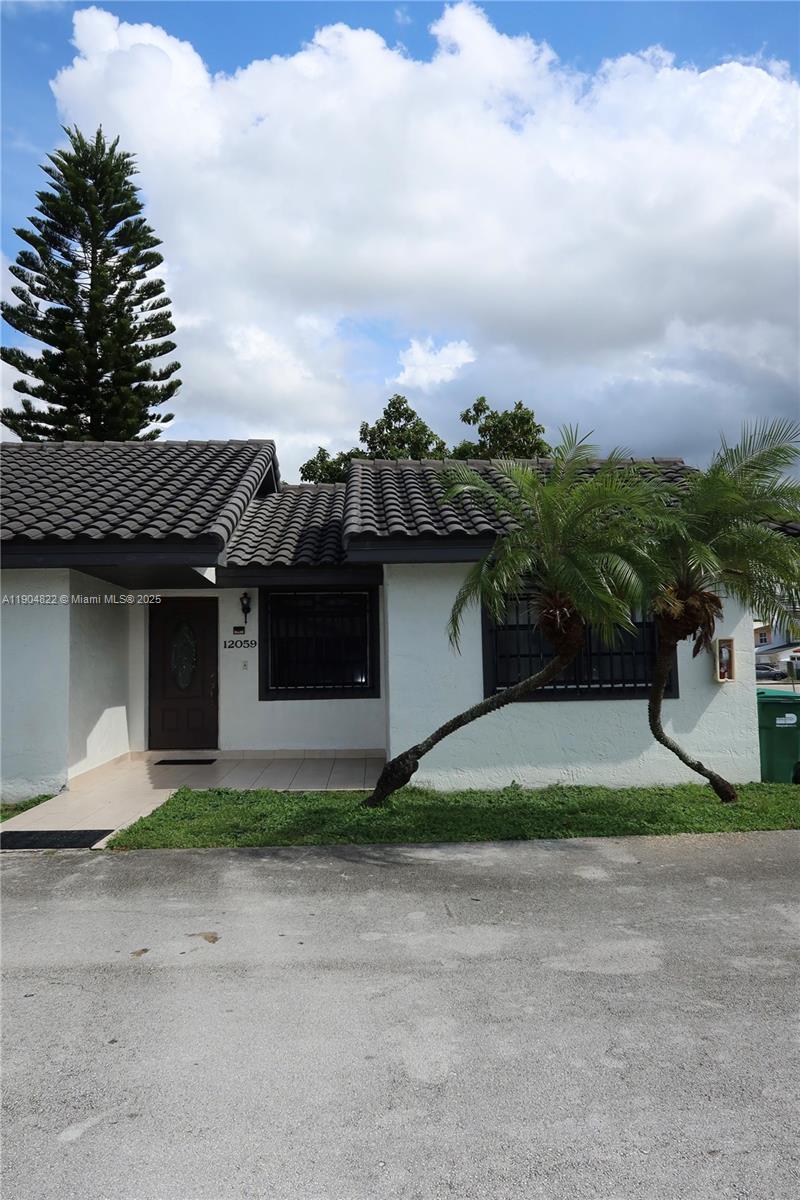 12059 Southwest 10th Street, Unit 201 Miami, FL 33184 - Photo 2 of 17 a white house with a yard and plants