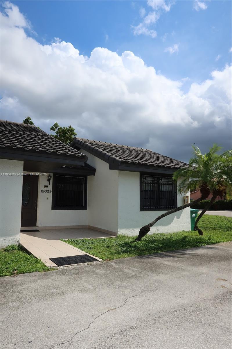 12059 Southwest 10th Street, Unit 201 Miami, FL 33184 - Photo 3 of 17 a front view of a house with a yard and garage