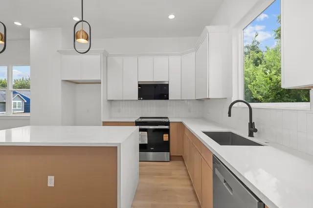 a kitchen with stainless steel appliances granite countertop a stove a sink and a microwave