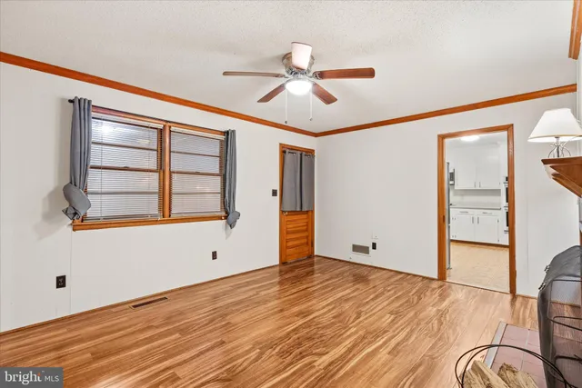 a view of empty room with wooden floor and fan