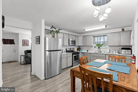 a kitchen with granite countertop a refrigerator a stove a sink dishwasher a dining table and chairs with wooden floor
