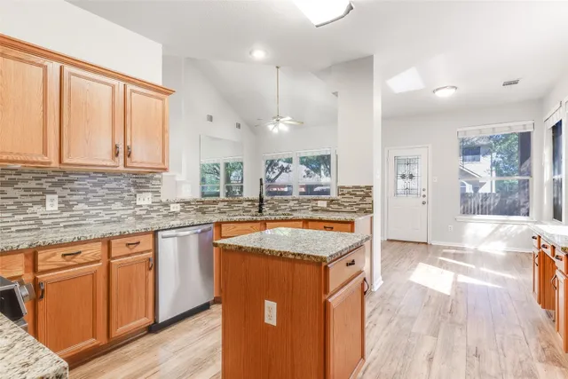 a kitchen with stainless steel appliances granite countertop a sink a stove and a wooden floors