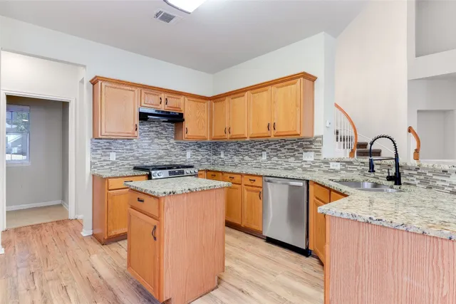 a kitchen with stainless steel appliances granite countertop a sink stove and wooden cabinets