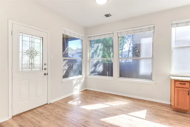 a view of an empty room with a window and wooden floor