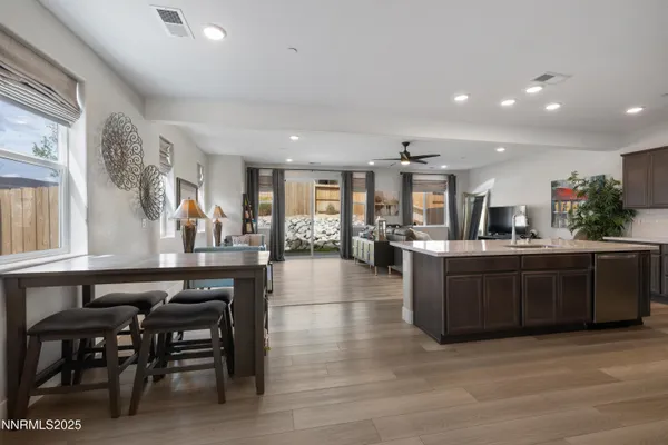 a kitchen with stainless steel appliances a table chairs refrigerator and wooden cabinets
