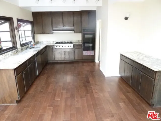 a kitchen with stainless steel appliances granite countertop a wooden cabinets and a stove