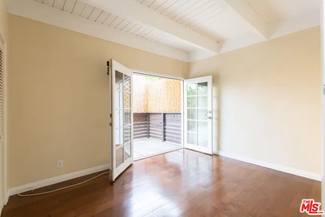 an empty room with wooden floor and windows with curtains