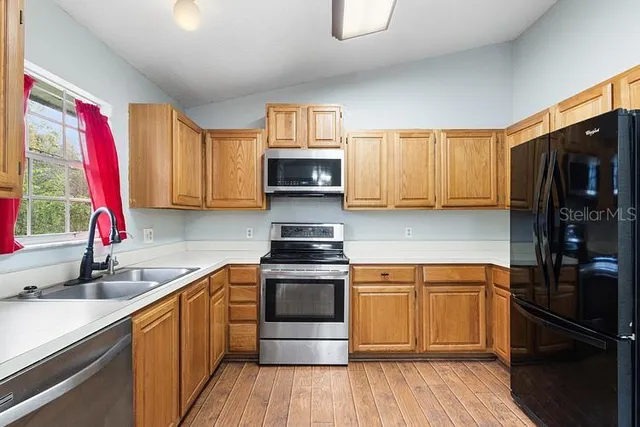 a kitchen with a sink wooden floor and a stove top oven