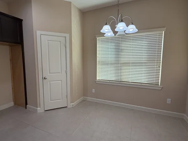 an empty room that has a window and a chandelier