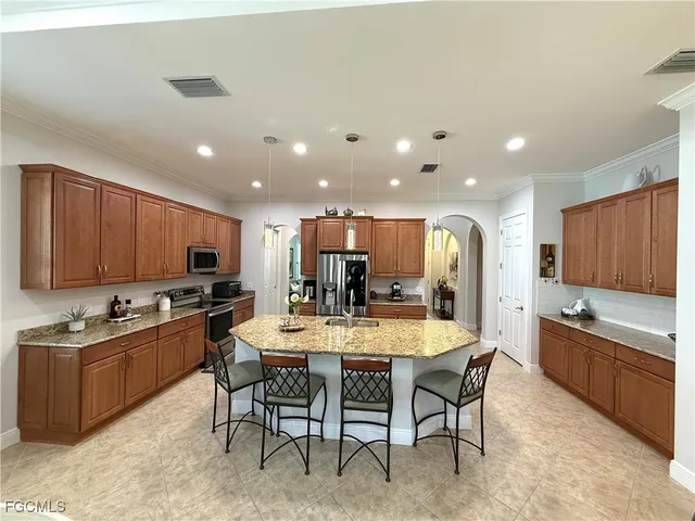 a dining room with stainless steel appliances kitchen island granite countertop a table chairs and a window
