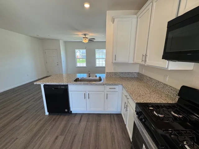 a kitchen with granite countertop white cabinets and a sink