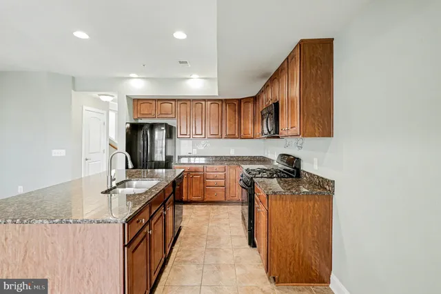 a kitchen with granite countertop a sink a stove and cabinets
