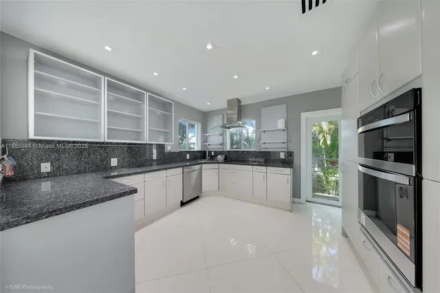 a large kitchen with stainless steel appliances kitchen island granite countertop a stove and a sink