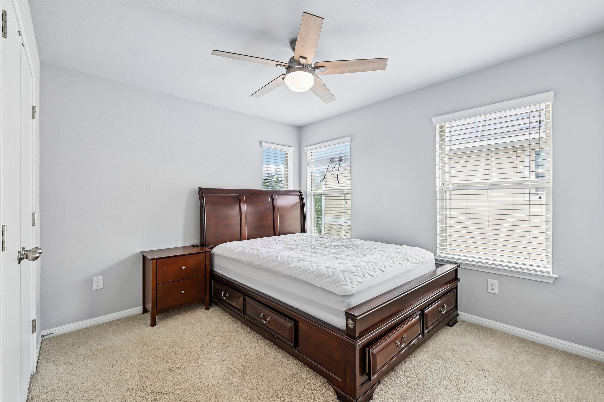 387 Guemal Road Buda, TX 78610 - Photo 24 of 39 Neutral tone wall paint, flush-mount ceiling fan with integrated lighting, wood-finish flooring, white baseboards, and multiple windows with blinds