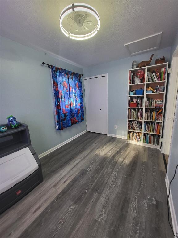 995 Emerald Drive Mount Dora, FL 32757 - Photo 20 of 33 a view of an empty room with bookshelf and wooden floor