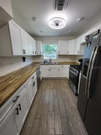 a kitchen with granite countertop wooden floors appliances and cabinets