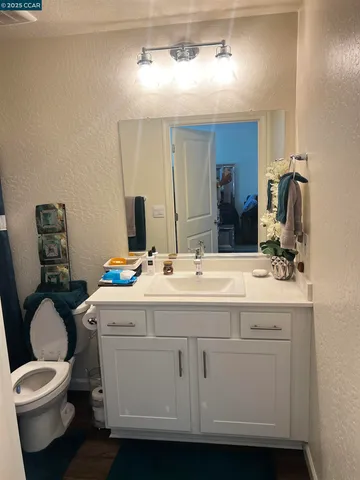 a bathroom with a granite countertop toilet sink and mirror