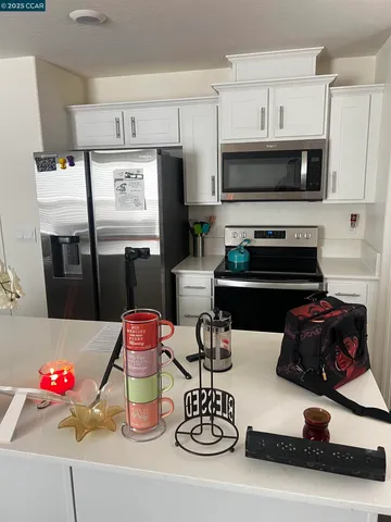 a kitchen with stainless steel appliances kitchen island granite countertop a stove and white cabinets