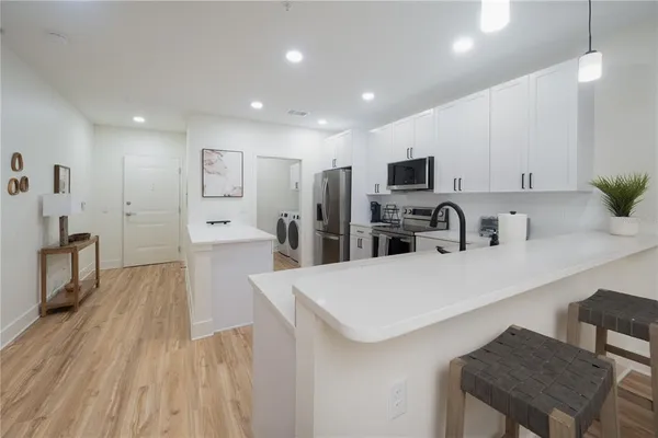 a large kitchen with kitchen island a stove a refrigerator a sink a dining table and chairs with wooden floor