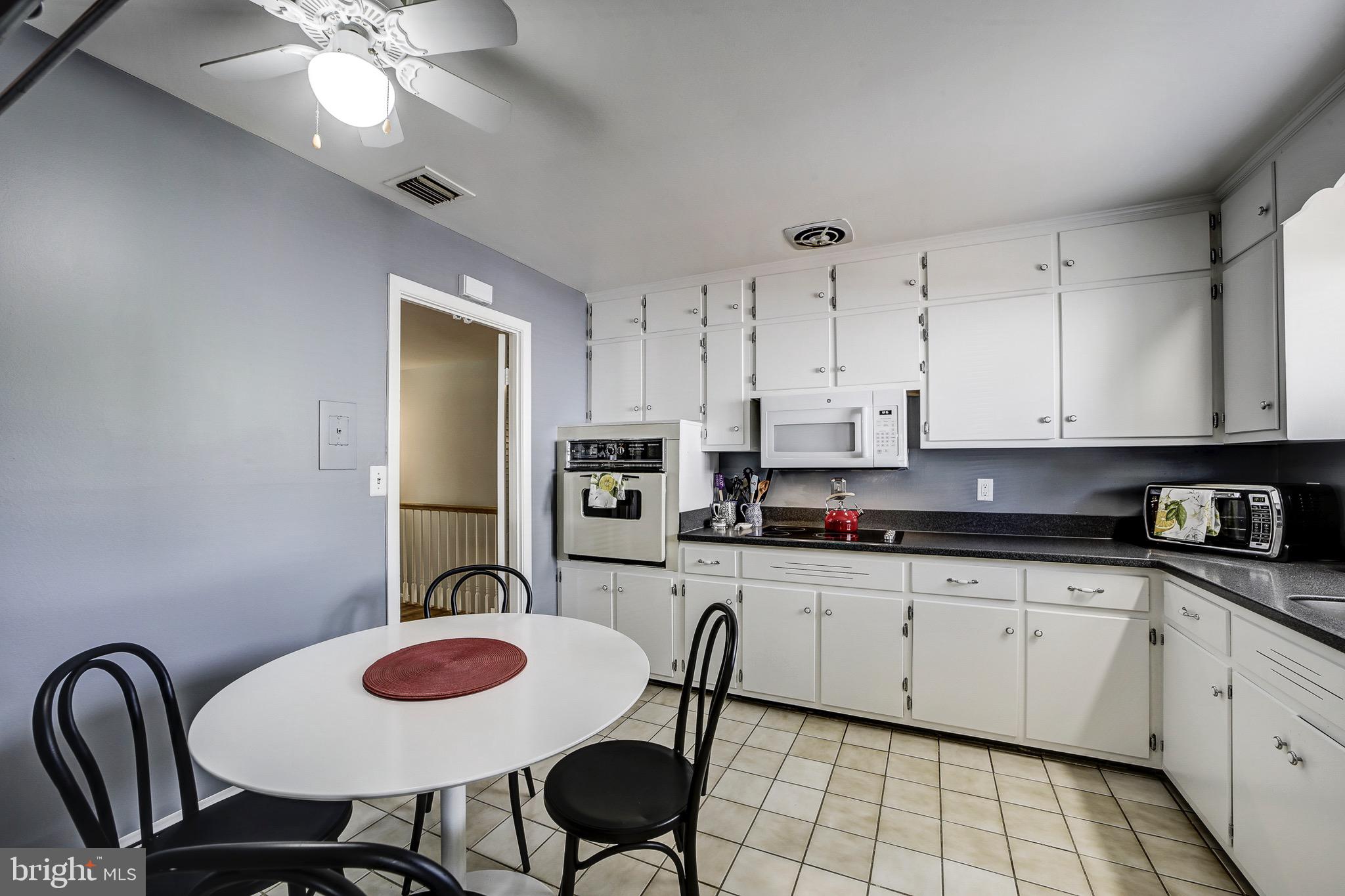6326 Rockhurst Road Bethesda, MD 20817 - Photo 12 of 32 a kitchen with stainless steel appliances granite countertop a sink a stove a dining table and chairs with wooden floor
