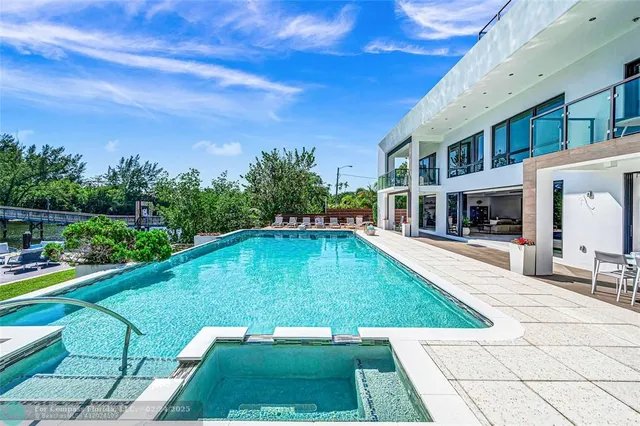 a swimming pool with lawn chairs and plants